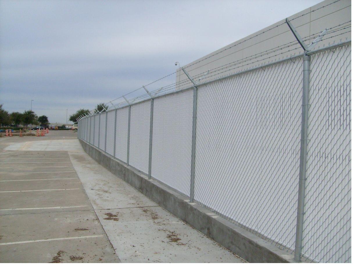 Commercial security fence with privacy slats and barbed wire