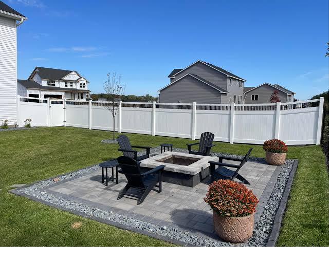 White vinyl privacy fence framing a backyard fire pit patio